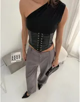 Corset negro de cuero sintético con cierre de cordones frontales y top asimétrico de un hombro.