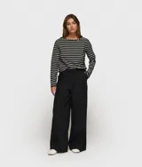 Pantalón ancho negro de corte relajado, confeccionado en mezcla de algodón y lino. Presenta cinturilla elástica de punto con cordón y trabillas, bolsillos laterales inclinados, etiqueta sobre el bolsillo izquierdo, minirayas bordadas bajo el bolsillo izquierdo y un bolsillo de ribete doble en la espalda.