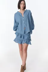 Camisa celeste de lino con botones, mangas largas abullonadas y detalles de crochet en el frente y los puños.
