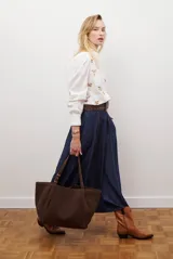 Falda larga de jean azul oscuro, corte acampanado con paneles y costuras visibles.