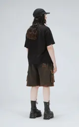 Bermuda estilo cargo oversize de algodón, con proceso de desgaste que genera un efecto degradado de negro a marrón óxido. Presenta recortes y bolsillos laterales con tapa.