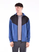 Campera deportiva azul con paneles negros en la parte superior y capucha. Cierre frontal con cremallera.