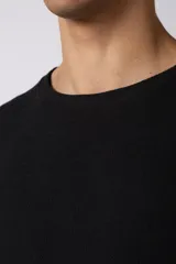 Remera negra de tejido tipo lino, corte holgado y cuello redondo. Sin estampas ni bordados.