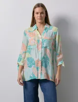 Camisa estampada con hojas en tonos celeste, naranja y verde. Tiene cuello con solapa, abertura central con botones, bolsillos aplicados en la parte delantera y mangas 3/4 con lazo.