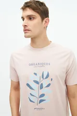 Remera color rosa pálido de manga corta con cuello redondo y estampado frontal con texto y diseño floral en tonos azules.
