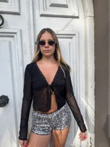 Top negro traslúcido de mangas largas con escote en V y lazo en el centro.