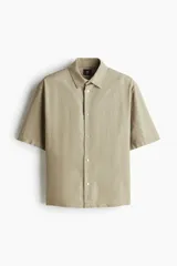 Camisa color beige de manga corta con cuello inglés y tapeta con botones. Corte holgado.