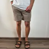 Bermuda color verde militar, de corte recto y largo a la rodilla, con cintura ajustable con cordón y bolsillos laterales. Confeccionada en simil lino.