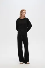 Buzo negro de punto canalé, corte holgado, cuello redondo y mangas largas.