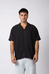 Camisa negra de lino con cuello cubano, manga corta y corte recto.