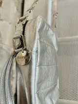 Bandolera plateada pequeña con diseño capitoneado, correa regulable con diseño combinado entre cintas de algodón, cuero y aritos metálicos.