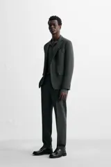 Pantalón de vestir azul marino, de corte slim fit, con bolsillos laterales y traseros. Se ajusta a la cintura con cinturón de cuero marrón.