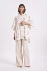 Camisa beige con estampado abstracto en tonos grises, azules y marrones. Corte oversize, mangas cortas y cuello clásico.