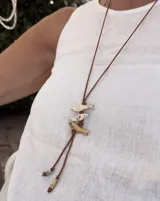 Gargantilla con hilo de algodón color camel y tres dijes de peces realizados en bronce, alpaca y plata 925.