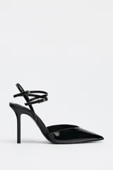 Zapato de tacón destalonado negro acharolado con tiras finas cruzadas ajustables con hebilla al tobillo y punta fina.