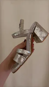 Sandalia dorada de cuero con doble tira delantera, horma cuadrada y ajuste con hebilla.