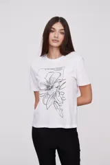 Remera blanca con estampado de hojas de ginkgo biloba en tonos naranja, beige y gris.