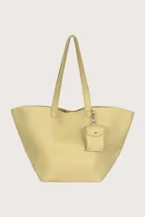 Bolso tipo shopper color amarillo con textura granulada y llavero colgante.