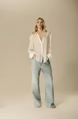 Camisa blanca de seda fluida, con silueta relajada, mangas largas con puño simple y cuello clásico.