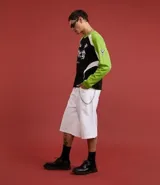 Remera de poliéster negra con mangas raglán verde lima y detalles blancos en los hombros. Presenta estampados con tipografías y gráficos en blanco en el frente.