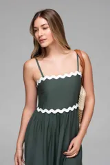 Vestido midi verde oscuro con tirantes finos y escote recto. Presenta detalles ondulados en color blanco en el escote, cintura y ruedo.