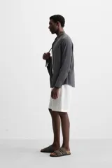 Bermuda regular fit negra confeccionada en tejido de lino. Cintura elástica ajustable con cordón y pliegues frontales. Bolsillos frontales y detalle de bolsillos traseros de plastrón.