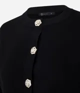 Cardigan blanco de tricot con cuello redondo, mangas largas y cierre frontal con botones florales metálicos. El bajo y los puños son acanalados.