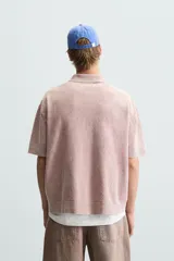 Polo de hombre color rosa, corte relaxed fit, tejido de punto con textura bouclé y mezcla de algodón. Tiene cuello solapa, cierre frontal con botones, manga corta y acabados en rib.