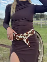 Faja ancha de cuero con estampado animal print de vaca, con tachas doradas y cierre con nudo.