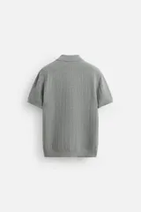 Polo gris de punto con textura, corte regular, cuello solapa y cierre frontal con botones.