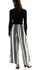 Pantalón palazzo de punto con textura a rayas verticales en blanco y negro. Tiene tiro alto, piernas rectas, elástico en la cintura y cordón para ajustar.