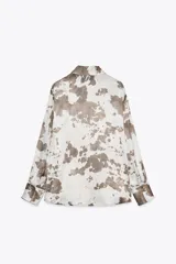 Camisa de manga larga con cuello solapa y estampado abstracto en tonos marrones y blancos. Cierre frontal con botones y bajo asimétrico.