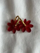 Aros colgantes plateados con dije de flor acrílica color dorado.
