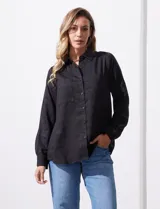 Camisa blanca de lyocell, marca Cyrus. Tiene cuello con solapa, abertura central con botones, mangas largas regulables con presilla y botón, y dos bolsillos delanteros aplicados.