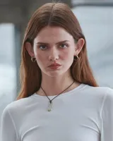 Collar con dije irregular dorado y cordón marrón ajustable.