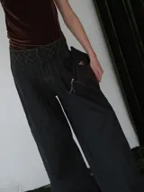 Pantalón vaquero de corte ancho, color crudo, con cintura alta y detalle de costuras cruzadas en la parte superior.
