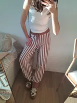 Pantalón de punto color marrón y blanco a rayas verticales, con corte holgado y cintura elastizada con cordón ajustable.