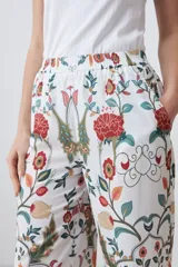 Pantalón de vestir blanco con estampado floral en tonos naranja, verde y rojo. Presenta un corte recto y cintura elástica. Incluye una chaqueta haciendo juego.
