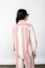 Sobrecamisa a rayas verticales rojas y blancas, de corte recto, con cuello camisero, cierre frontal con botones, mangas largas con puños abotonados y bolsillos de parche en el pecho.