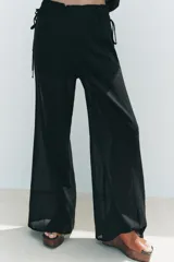 Pantalón negro de tiro alto con cintura elástica ajustable con cordones laterales, forro interior corto y pernera ancha.