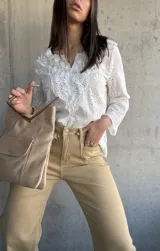 Blusa blanca de algodón con bordado broderie, escote en V y mangas largas.