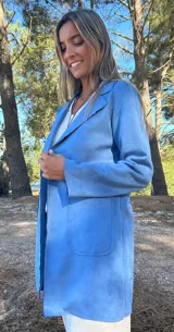 Chaqueta larga de mujer color celeste, con cuello solapa y bolsillos frontales. El material parece ser gamuza o piel sintética.
