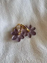 Aros colgantes dorados con forma de flor blanca.