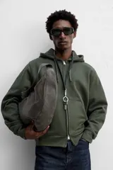 Bolso de hombro color marrón oscuro fabricado en piel con acabado craquelado. Tiene un compartimento principal con cierre de cremallera y un bolsillo interior con cremallera.