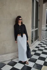 Pollera larga de viscosa con estampado de lunares blancos sobre fondo negro.