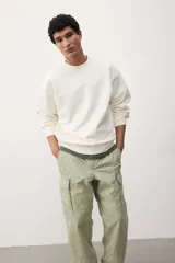 Pantalón cargo color verde claro, de corte relajado, con bolsillos laterales con solapa y botón a presión. Confeccionado en popelina de algodón con elástico en la parte posterior de la pretina y cierre con botón a presión.