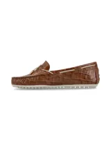 Mocasín color crema con textura de piel de cocodrilo, cordones de cuero marrón con punteras metálicas doradas y suela marrón de goma antideslizante.