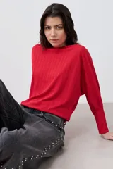 Blusa roja de tejido de punto acanalado, con escote barco y mangas dolman largas.