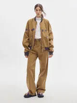 Pantalón de denim color marrón claro, de tiro alto, corte amplio y pinzas en la cintura.