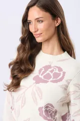Buzo tejido en jacquard color crema con estampado de rosas azules y hojas marrones. Tiene cuello redondo y puños de rib.